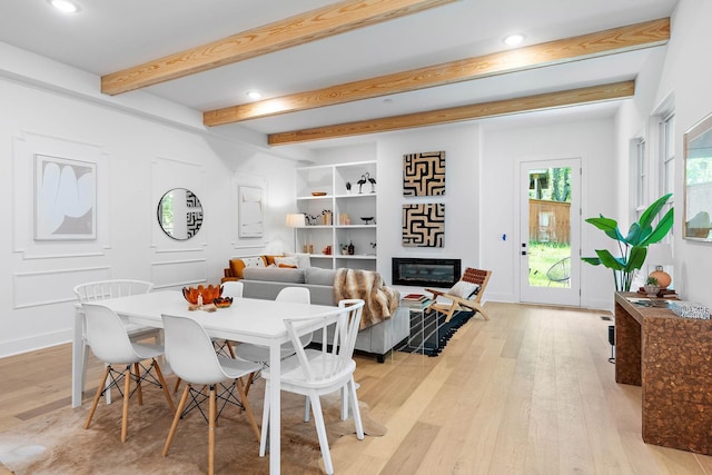 dining room with recessed lighting, beam ceiling, a glass covered fireplace, and light wood-style flooring