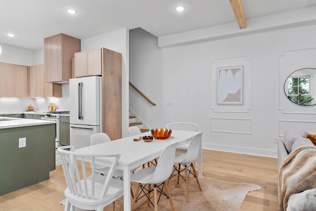 dining area with light wood-type flooring, recessed lighting, stairs, and beamed ceiling