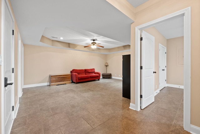 sitting room featuring a tray ceiling, baseboards, a ceiling fan, and tile patterned floors