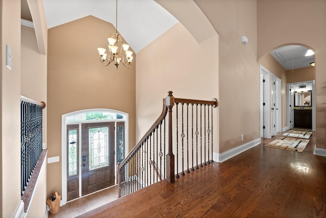 foyer entrance featuring baseboards, wood finished floors, a chandelier, and high vaulted ceiling
