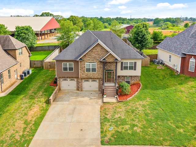 split foyer home featuring roof with shingles, an attached garage, a front lawn, stone siding, and concrete driveway