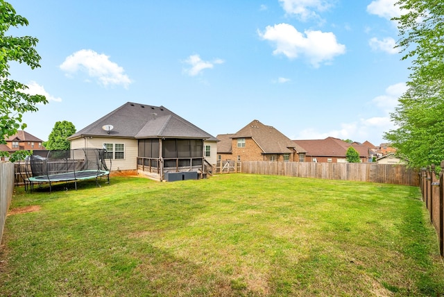 exterior space with a fenced backyard, a yard, a trampoline, and a sunroom