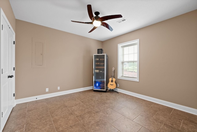 tiled empty room featuring ceiling fan, visible vents, baseboards, and electric panel