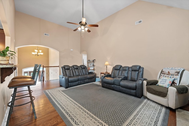 living room featuring visible vents, arched walkways, wood finished floors, and high vaulted ceiling