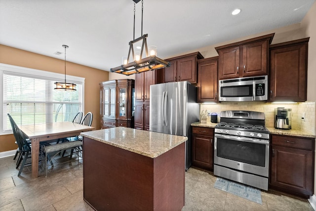 kitchen featuring light stone countertops, a center island, backsplash, a notable chandelier, and stainless steel appliances