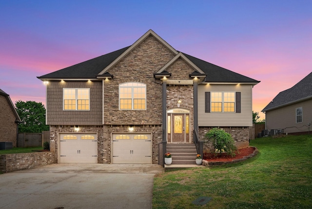 split foyer home featuring a garage, a front lawn, stone siding, brick siding, and concrete driveway