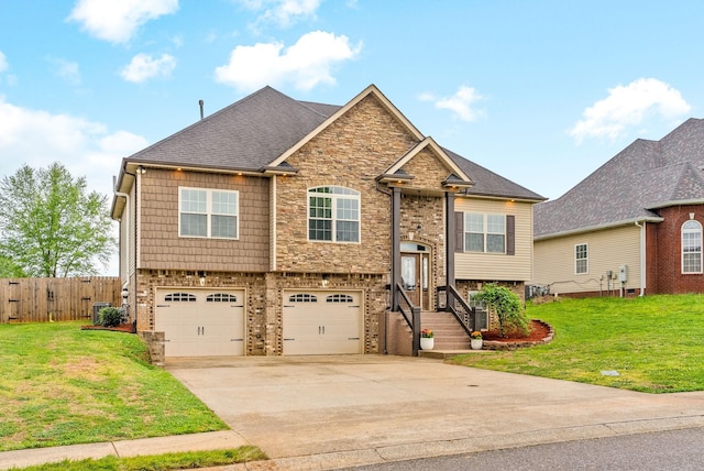 raised ranch with driveway, a front yard, fence, an attached garage, and stone siding