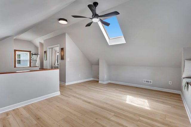 bonus room with vaulted ceiling with skylight, ceiling fan, visible vents, baseboards, and light wood finished floors