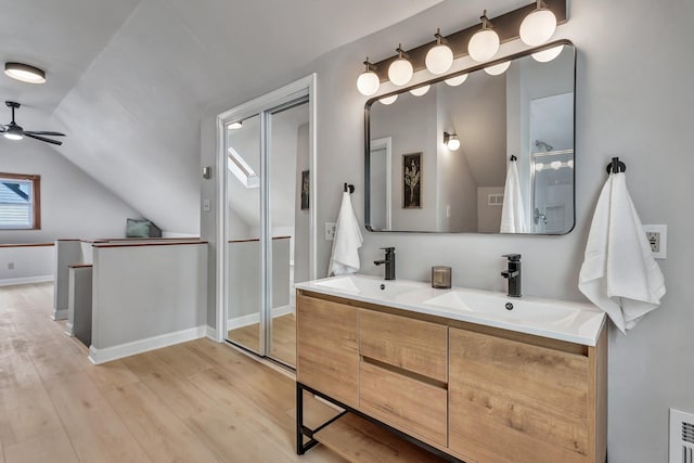full bathroom with a sink, vaulted ceiling, a ceiling fan, and wood finished floors