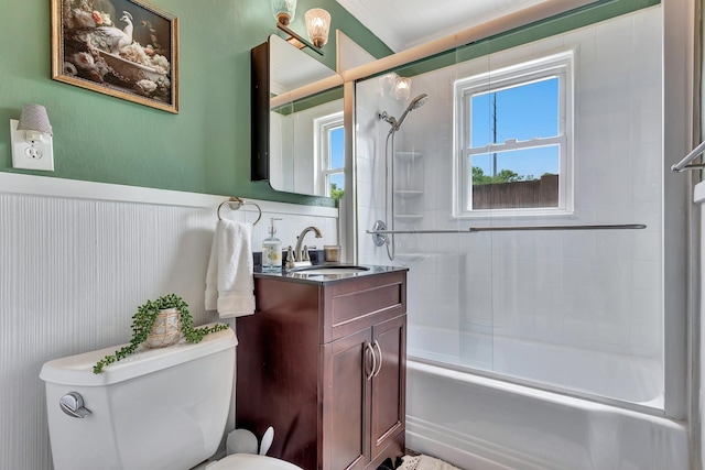 full bath featuring toilet, enclosed tub / shower combo, a wainscoted wall, and vanity