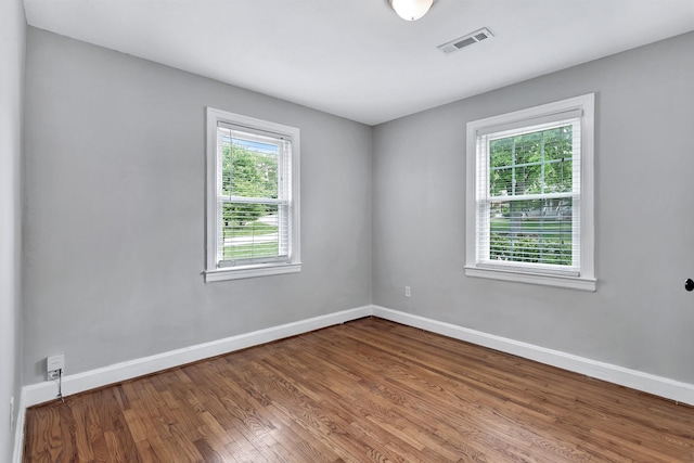 empty room with baseboards, wood finished floors, and visible vents