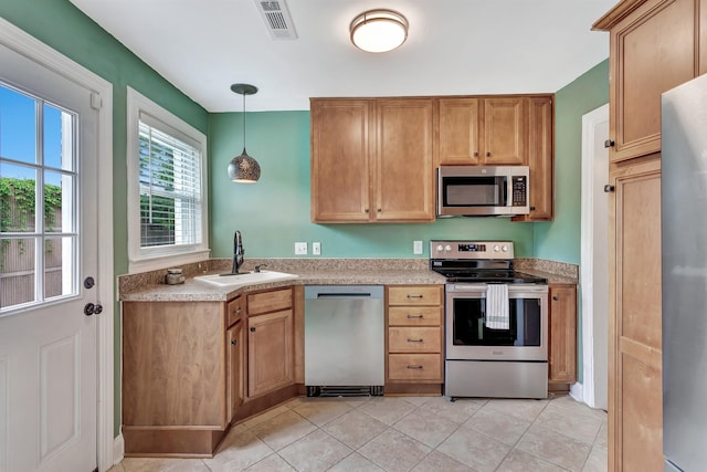 kitchen with visible vents, light countertops, a sink, decorative light fixtures, and stainless steel appliances