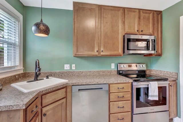kitchen featuring light countertops, decorative light fixtures, appliances with stainless steel finishes, and a sink