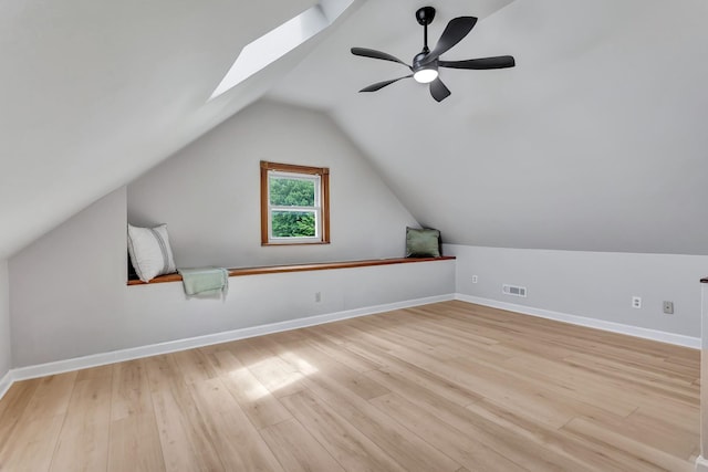 bonus room featuring visible vents, light wood finished floors, lofted ceiling with skylight, and baseboards