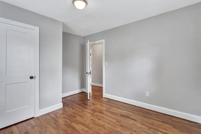 spare room with baseboards and wood finished floors