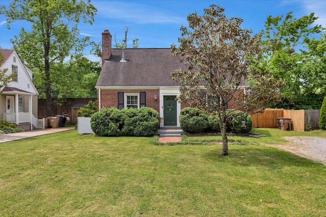 cape cod house featuring brick siding, fence, a front yard, and a chimney
