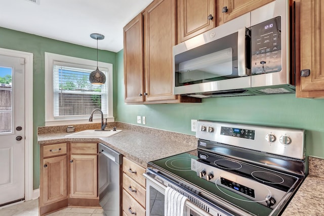 kitchen featuring light countertops, a sink, light tile patterned floors, hanging light fixtures, and stainless steel appliances
