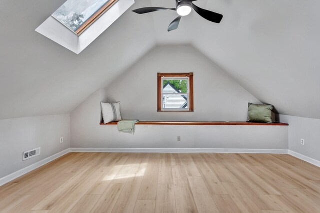 bonus room featuring vaulted ceiling with skylight, a ceiling fan, visible vents, wood finished floors, and baseboards