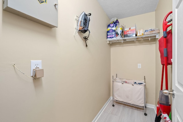 clothes washing area featuring baseboards and a textured ceiling
