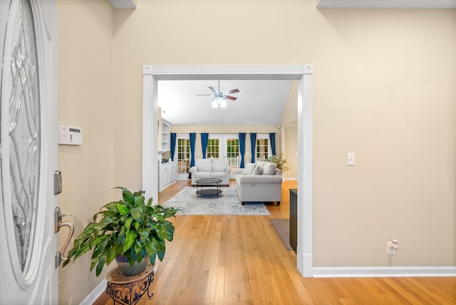 living area with a ceiling fan, baseboards, lofted ceiling, and light wood-style floors