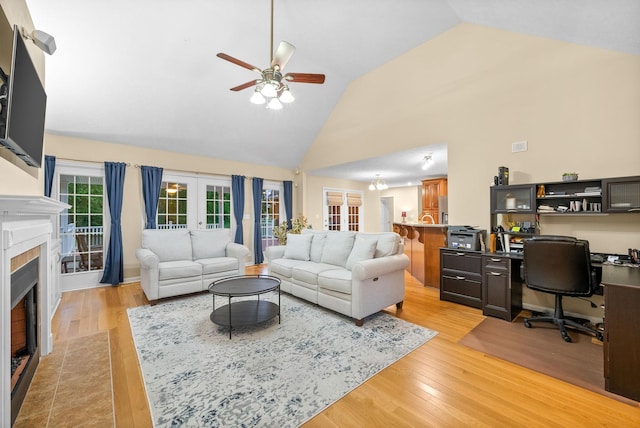 living area with a ceiling fan, light wood-style floors, french doors, and a tile fireplace