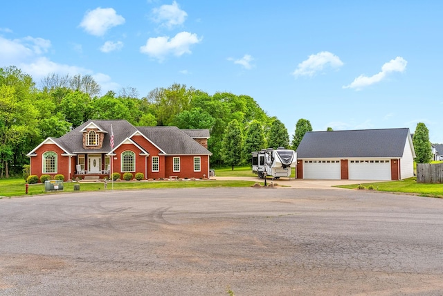 view of front of home with a detached garage, driveway, and a front yard
