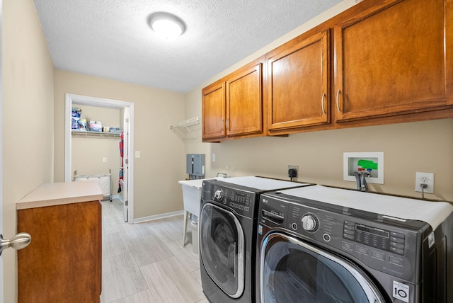 laundry area with baseboards, washer and clothes dryer, cabinet space, and a textured ceiling