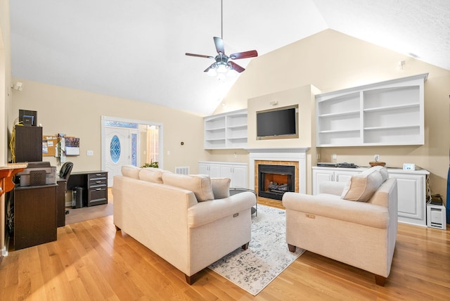 living room featuring ceiling fan, visible vents, a fireplace, vaulted ceiling, and light wood-style floors