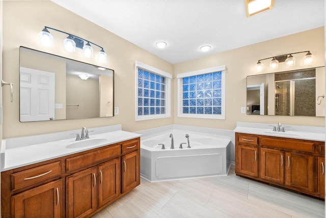 full bath with a sink, a shower stall, a garden tub, and two vanities