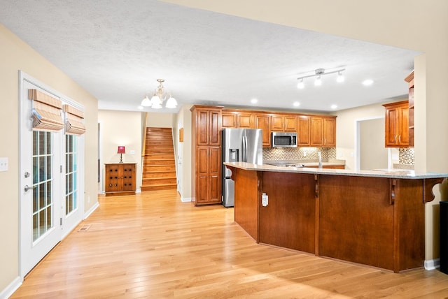 kitchen with brown cabinets, appliances with stainless steel finishes, tasteful backsplash, and a kitchen bar