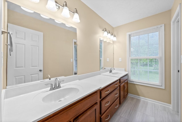 full bath with baseboards, a sink, and double vanity