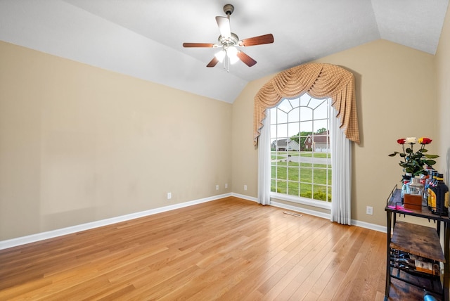 empty room featuring a ceiling fan, baseboards, light wood-style flooring, and lofted ceiling