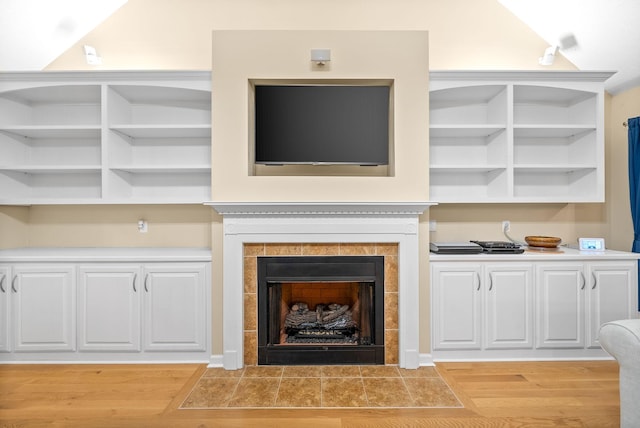 interior details with wood finished floors and a tile fireplace