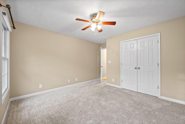 unfurnished bedroom featuring carpet flooring, baseboards, ceiling fan, and a closet