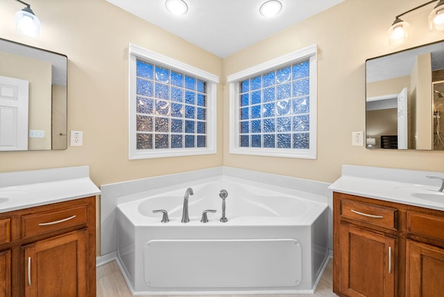 full bath with a sink, a garden tub, and two vanities