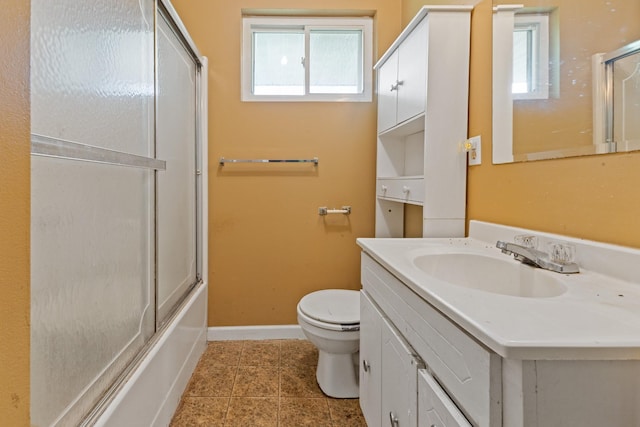 bathroom featuring vanity, toilet, tile patterned floors, baseboards, and bath / shower combo with glass door