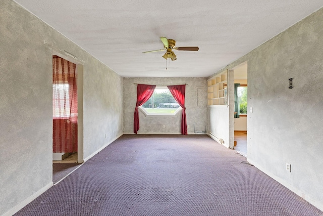 carpeted spare room featuring baseboard heating and a ceiling fan