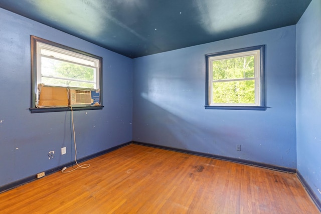 unfurnished room featuring baseboards, wood finished floors, and cooling unit