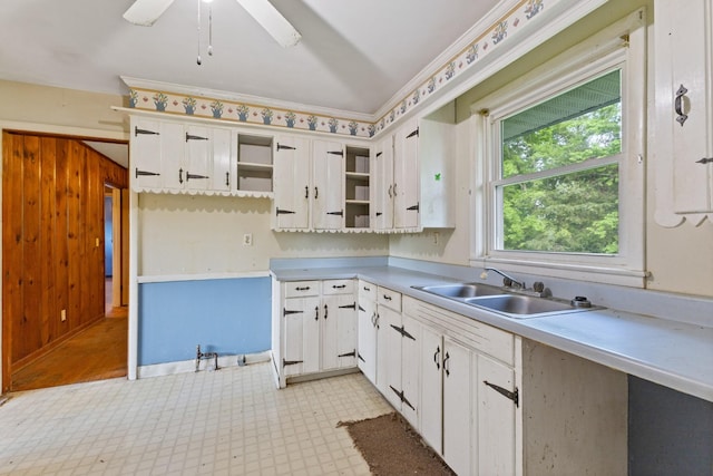 kitchen with open shelves, a sink, light countertops, light floors, and white cabinetry