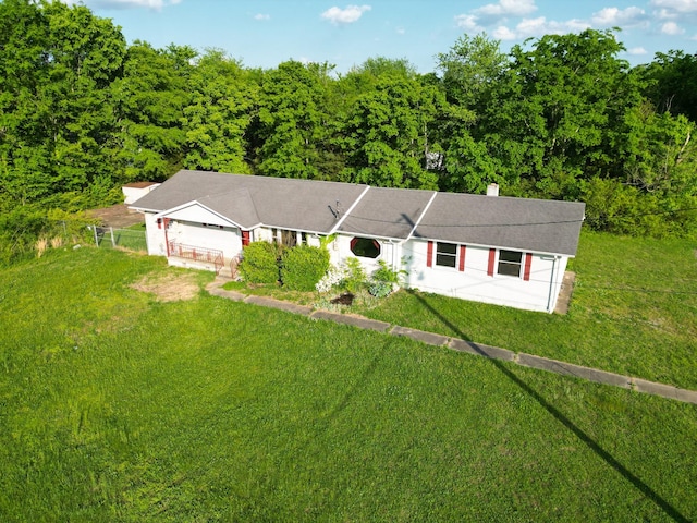 view of front of property with a garage, a front lawn, fence, a chimney, and a wooded view