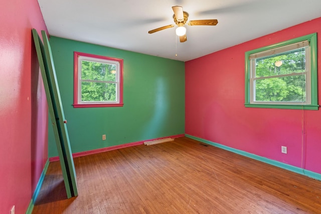 unfurnished room featuring baseboards, ceiling fan, wood finished floors, and visible vents