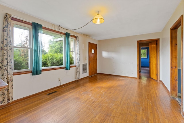 interior space with baseboards, visible vents, heating unit, and light wood finished floors