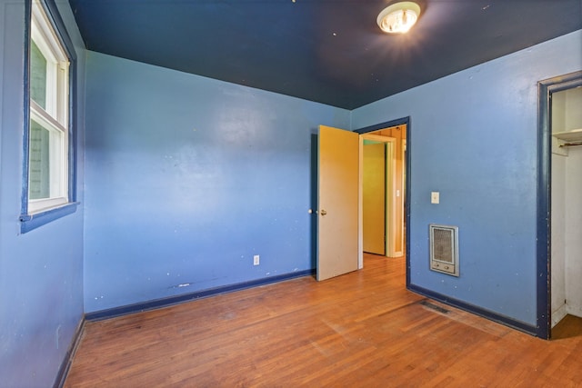 unfurnished bedroom featuring baseboards, wood finished floors, and visible vents