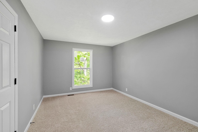carpeted spare room featuring baseboards and visible vents
