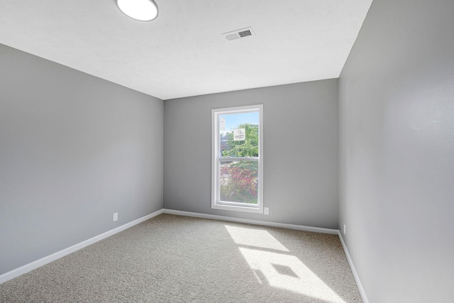 spare room with visible vents, carpet, and baseboards