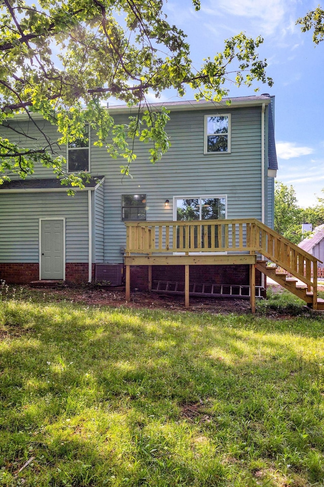 back of property featuring a yard, a wooden deck, and stairs