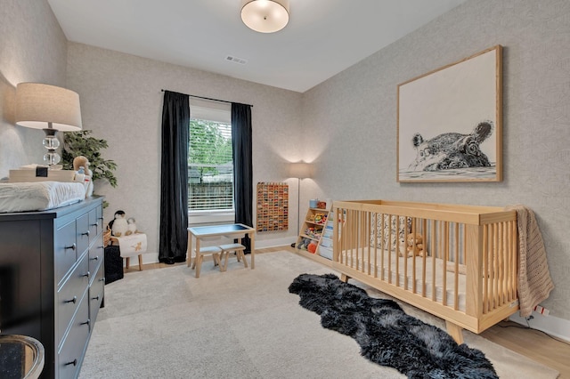 carpeted bedroom featuring a nursery area, baseboards, and visible vents