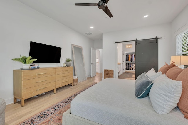 bedroom with recessed lighting, visible vents, a barn door, and light wood finished floors