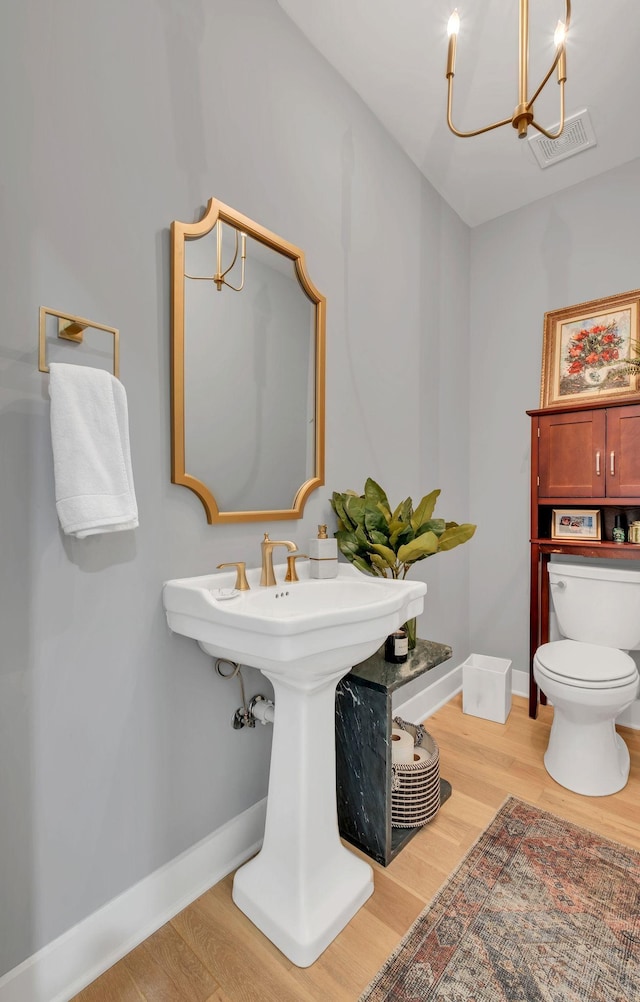 bathroom featuring visible vents, wood finished floors, baseboards, toilet, and a chandelier