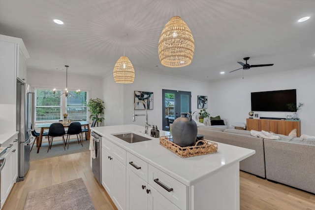 kitchen with a sink, light countertops, stainless steel appliances, and light wood-style flooring
